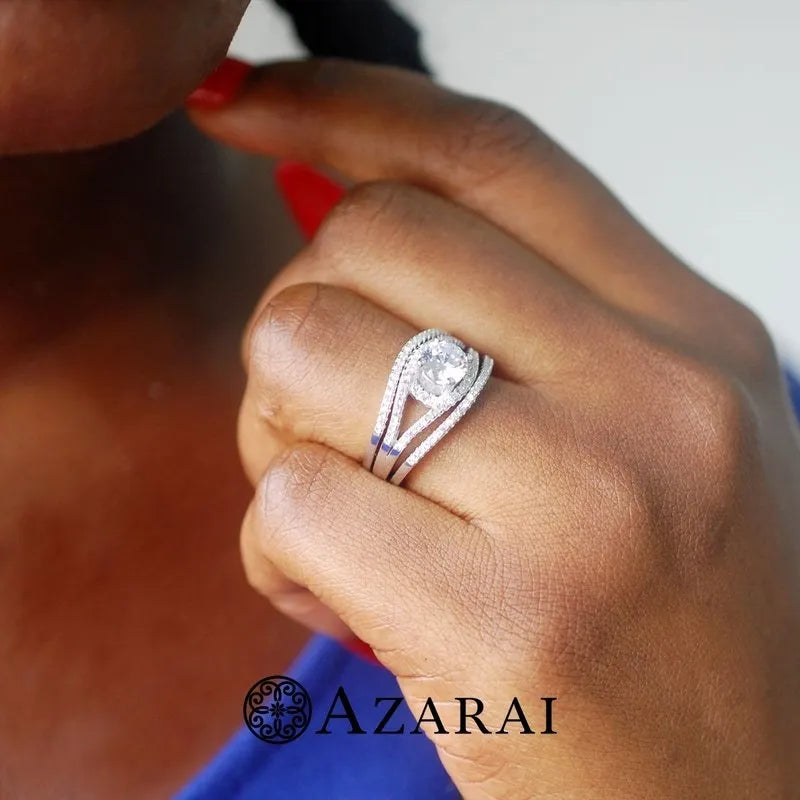 A person with red nails is wearing a Raquel sterling silver bridal set featuring a round diamond, and at the bottom, there's a logo that reads "Azarai.