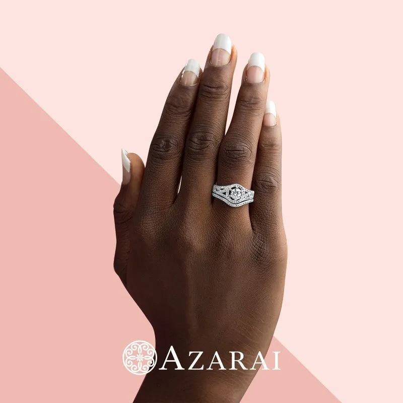 A hand adorned with the stunning Zhane sterling silver bridal set, now on clearance, graces the image against a soft pink backdrop. The elegant script of "AZARAI" is elegantly positioned at the bottom, capturing attention with its refined allure.