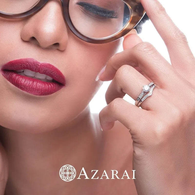 A woman with glasses wears red lipstick and touches her face, displaying a dazzling diamond ring from the Sofia sterling silver bridal set collection. The brand name Azarai is at the bottom.