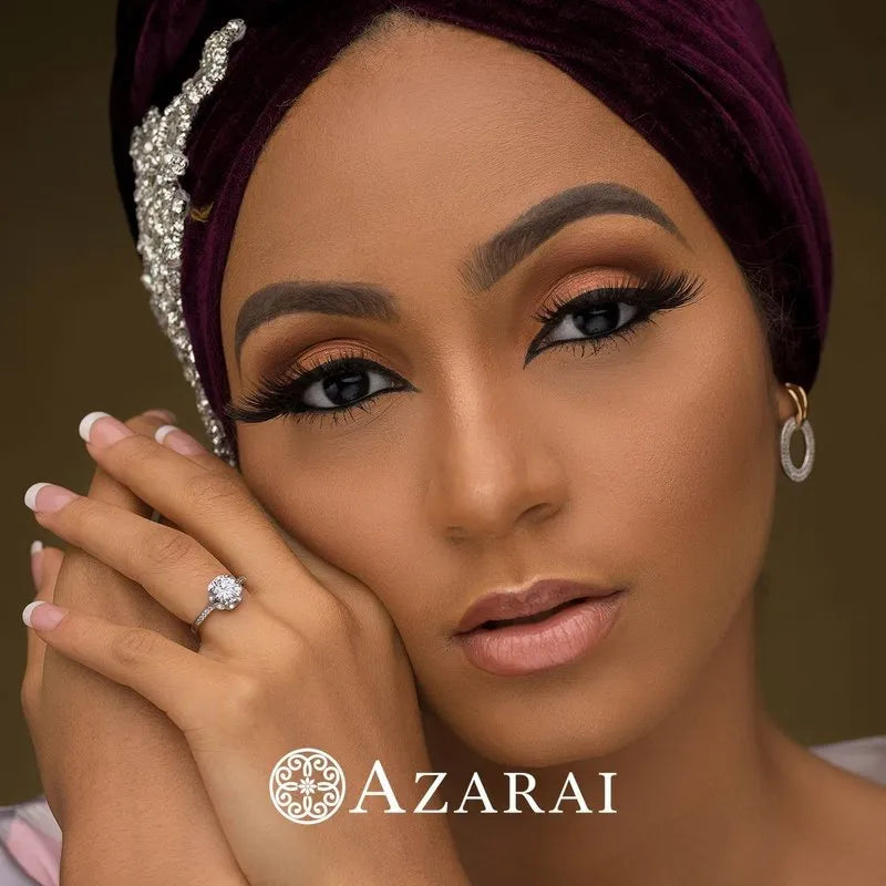 A woman adorned with a purple turban and hoop earrings displays the Anais sterling silver engagement ring elegantly on her hand, which rests gently on her face. The word "Azarai" appears at the bottom.