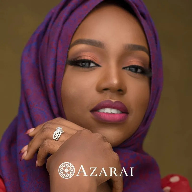 A woman in a purple headscarf elegantly showcases her finger adorned with the Miele sterling silver bridal set. The word "Azarai" is at the bottom.