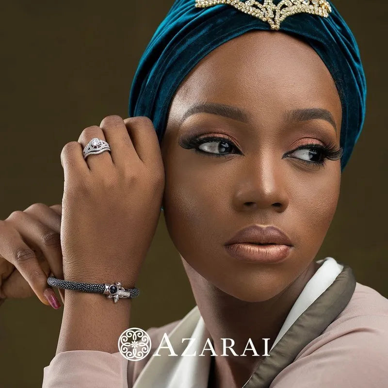 A person wearing a blue velvet headwrap, a sterling silver bridal set from the Zhane collection on clearance, and looking to the side. The word "AZARAI" is at the bottom.