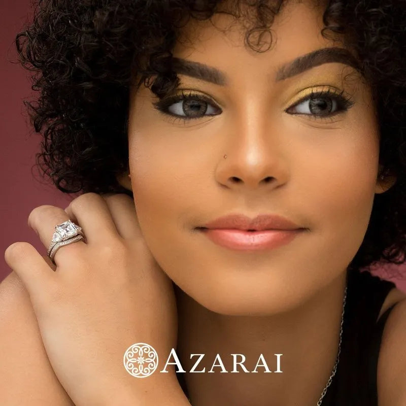 A close-up reveals a person with curly hair and gold eyeshadow, adorned with a diamond ring from the exquisite Guinevere sterling silver bridal set. "Azarai" is elegantly scripted at the bottom.