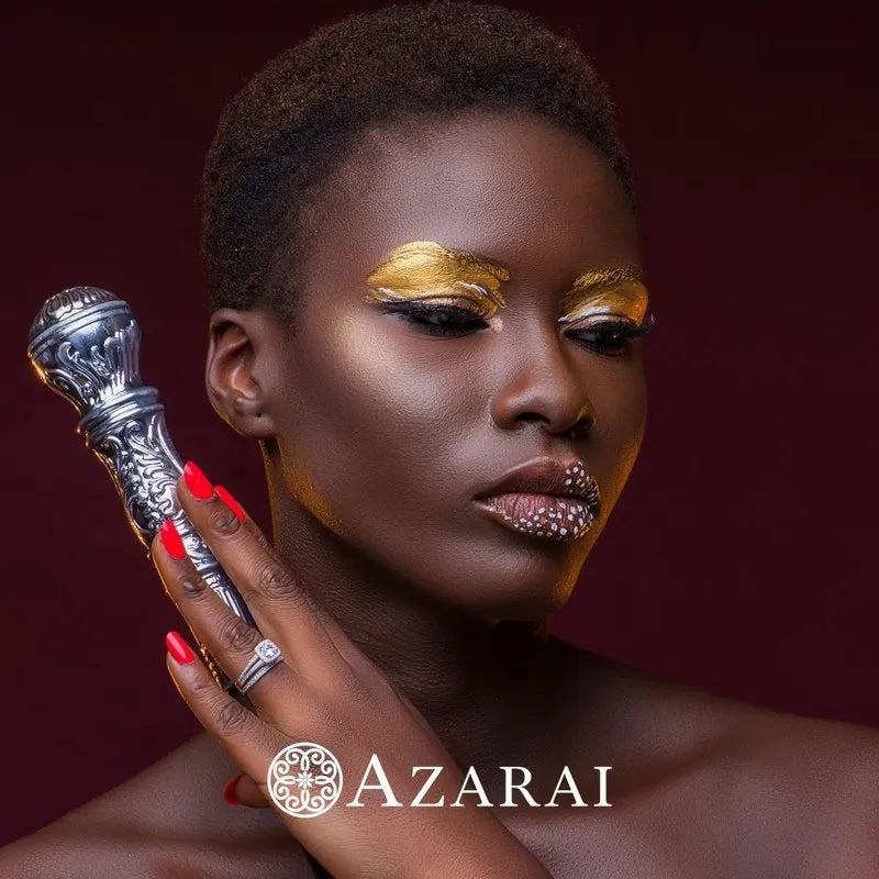 A person with metallic eyeshadow and lipstick holds a decorative silver object, perfectly enhancing the Eva sterling silver bridal set on clearance. The logo reads "AZARAI.