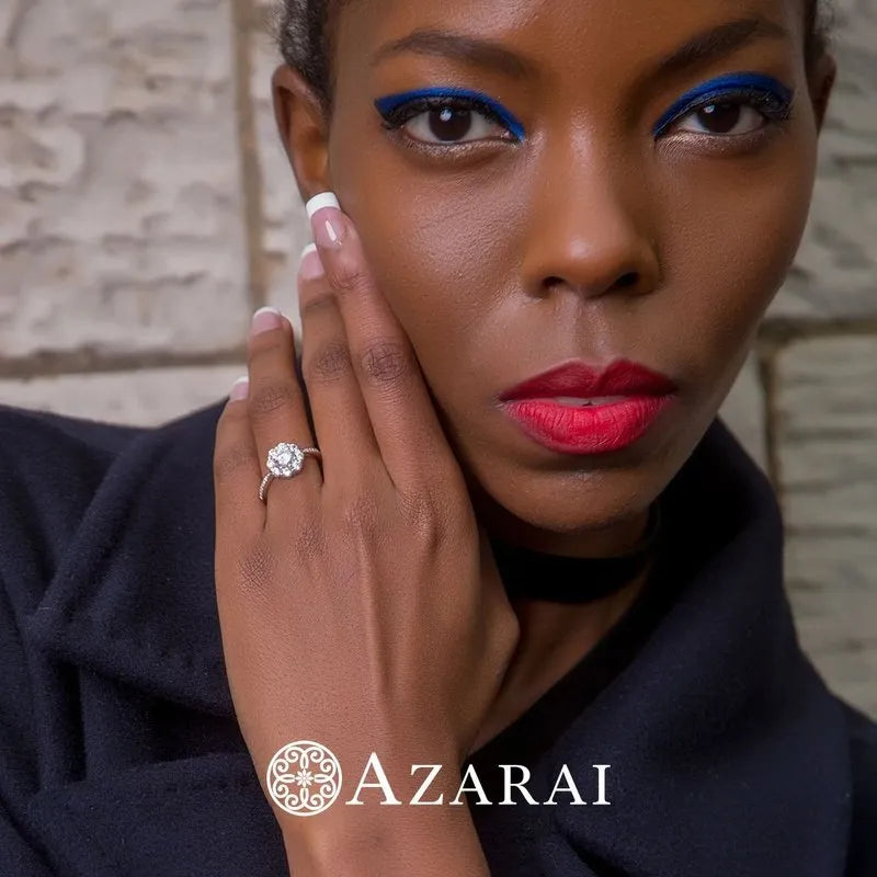 Adorned with vibrant makeup and an elegant Charlotte sterling silver engagement ring on clearance, a person showcases the "AZARAI" logo at the bottom.