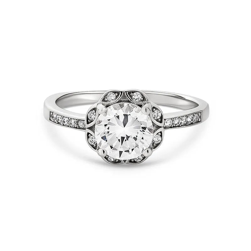 Introducing the Anais sterling silver engagement ring: a breathtaking piece that showcases a dazzling large round diamond at its center. It is beautifully surrounded by smaller diamonds and elegantly embellished with additional diamonds along its sophisticated band, capturing the timeless allure of Anais.