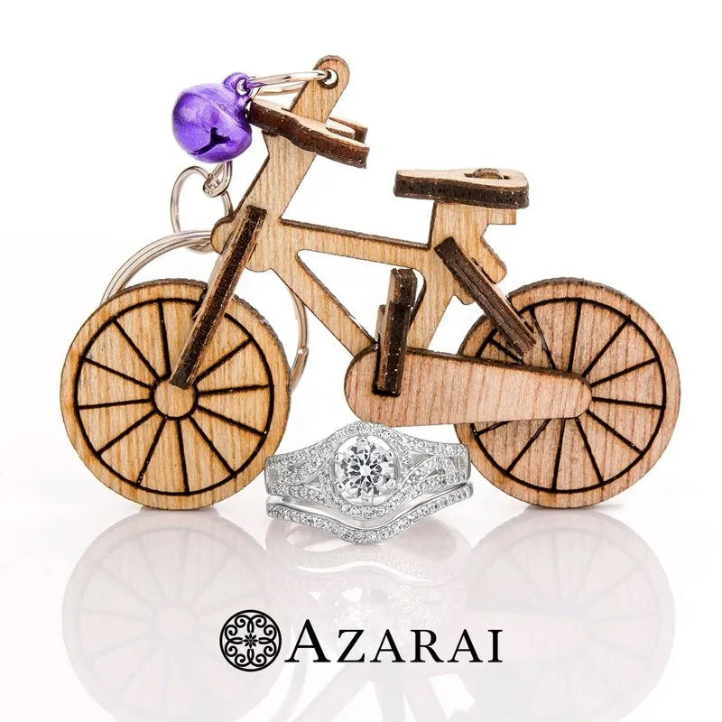 A wooden bicycle keychain with a purple bell sits beside the stunning Zhane sterling silver bridal set. The word "Azarai" is elegantly printed below, suggesting a clearance sale opportunity.