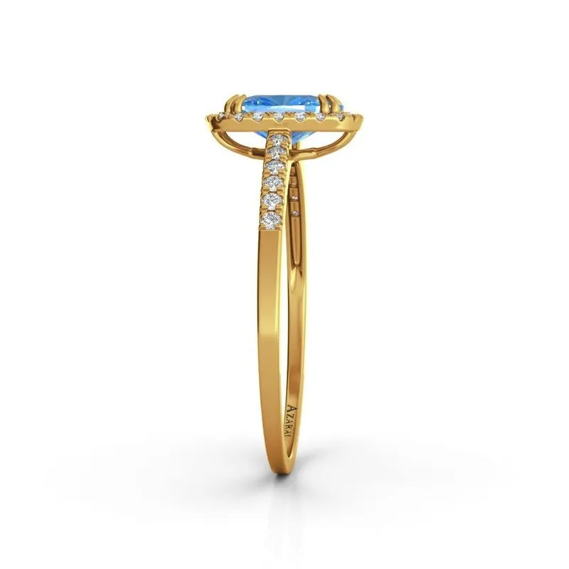 The Adeline 9kt gold engagement ring features a captivating central blue gemstone, accented with small diamonds along the band, and is elegantly presented in a side view angle.