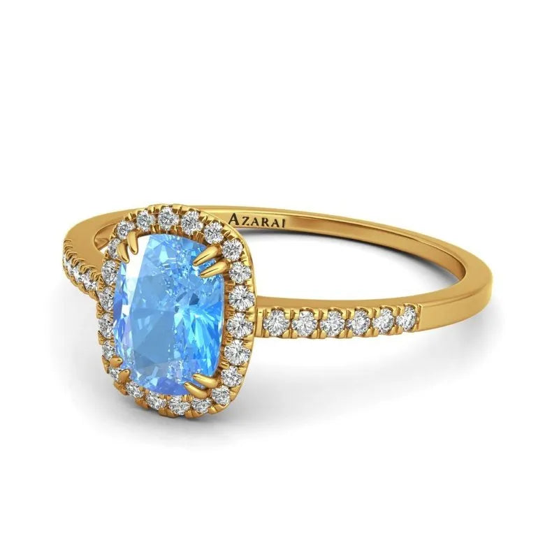 The Adeline 9kt gold engagement ring showcases a captivating large blue gemstone, beautifully positioned on a 9kt gold band embellished with smaller clear stones.