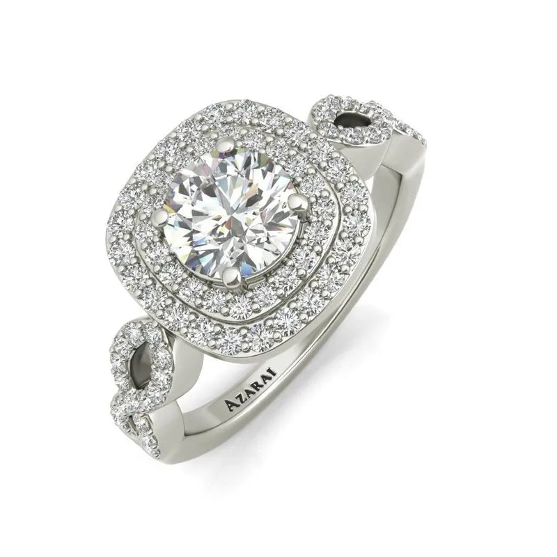 The Astrid sterling silver engagement ring showcases a large central diamond, surrounded by two layers of smaller diamonds, and features a twisted band design that exudes elegance. An ideal choice for those who appreciate timeless beauty.