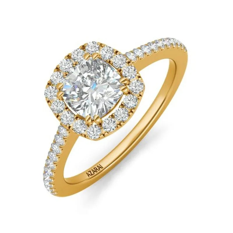 Presenting the Celeste 14kt gold engagement ring: a breathtaking piece showcasing a cushion-cut diamond centerpiece, surrounded by radiant smaller diamonds. Crafted from exquisite 14kt gold, its band is gracefully embellished with additional sparkling diamonds.