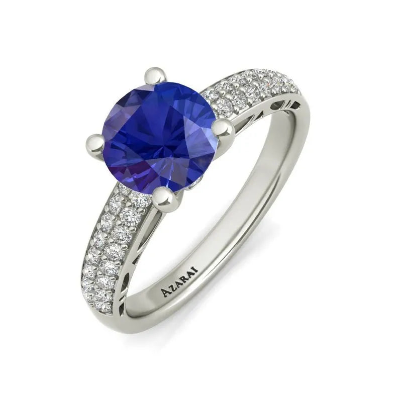 Introducing the Dakota sterling silver engagement ring, now on clearance, featuring a large blue gemstone surrounded by small clear stones on the band. It's a perfect choice for the modern bride seeking elegance and style.