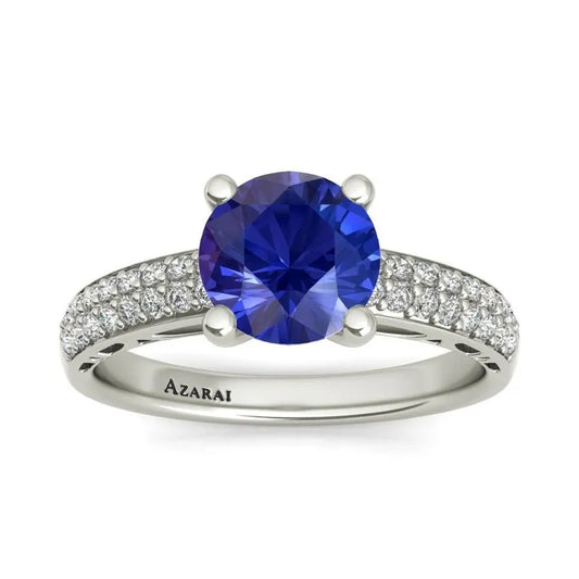 A Dakota sterling silver engagement ring, currently on clearance, showcases a large blue gemstone at its center, adorned with small clear stones along the band. The word "Azarai" is elegantly engraved inside, making it an ideal choice for the modern bride seeking elegance.