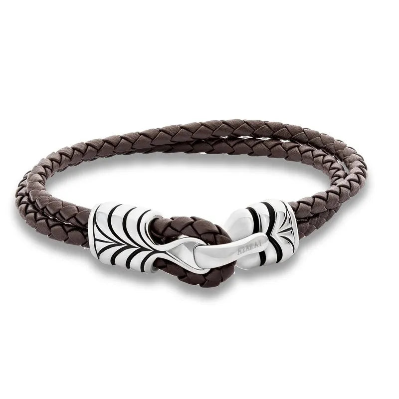 The Osiris leather bracelet for men features a brown braided design with a metal decorative clasp adorned with intricate leaf-like engravings, elegantly presented in gift packaging. Ideal for any occasion, this accessory is available for nationwide delivery.