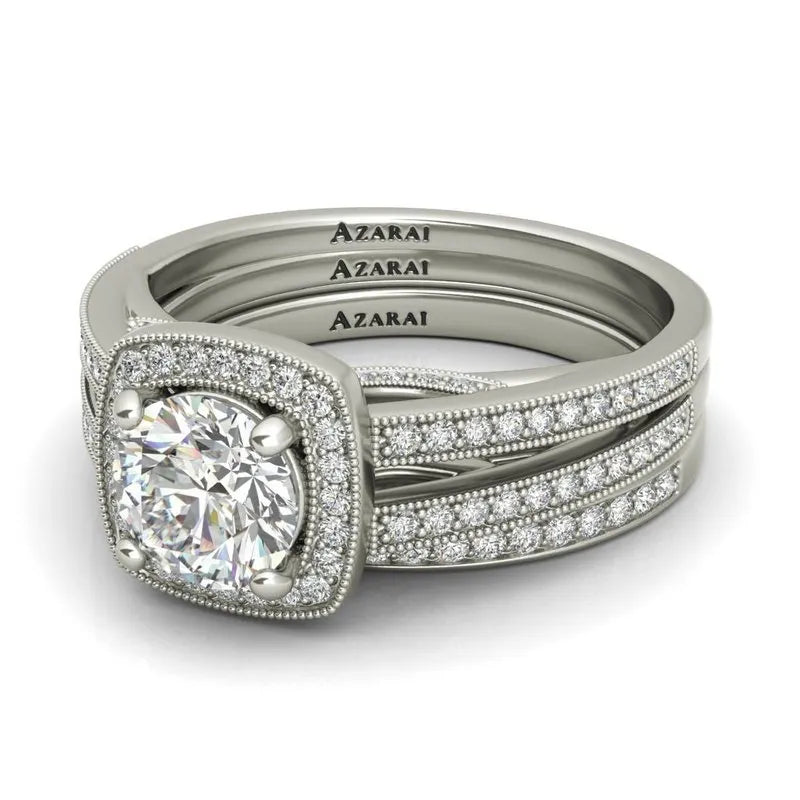 An elegant Eva sterling silver bridal set on clearance, featuring a large central diamond surrounded by intricate smaller diamonds, all engraved with the word "AZARAI.