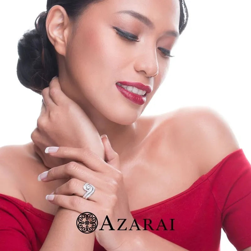 A person wearing a red off-shoulder top gazes downward, their hands near their face adorned with the Katrina sterling silver bridal set, which is currently on clearance. Complementing their look is bold red lipstick and the elegant "Azarai" logo at the bottom.