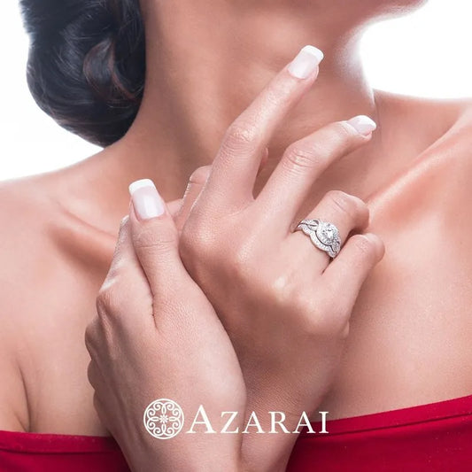 A woman with manicured nails showcases a stunning diamond ring on her finger, which is part of the exquisite Louisa sterling silver bridal set currently on clearance, against a plain background. The word "Azarai" is elegantly displayed at the bottom.