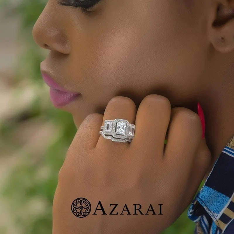 A close-up of a person wearing the Manhattan sterling silver bridal set, featuring a large square gemstone accented by smaller stones, gently holding their chin. The word "AZARAI" accompanied by a decorative emblem at the bottom embodies the chic elegance of Manhattan.