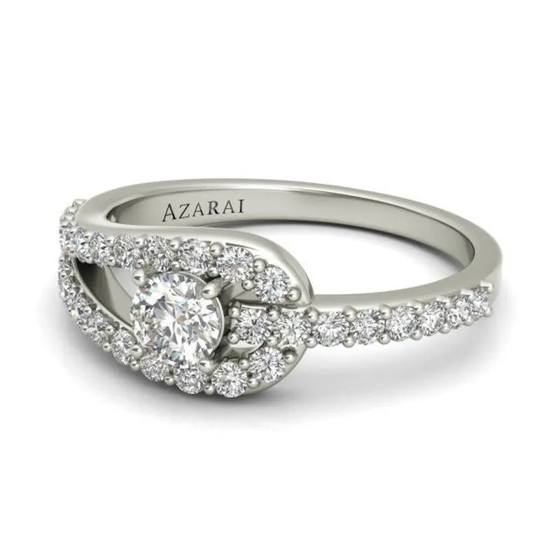 The Paloma sterling silver engagement ring showcases a breathtaking round center stone surrounded by a halo design, elegantly accented with small diamonds on the band, offering timeless elegance and sophistication.