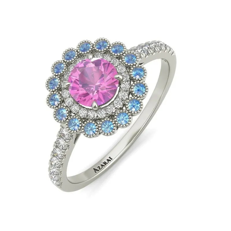 Introducing the exquisite Portia 9kt gold engagement ring: a stunning piece featuring a pink central gemstone, embraced by blue stones and encircled with delicate diamonds. Set on a silver band engraved with "AZARAI," this masterpiece redefines elegance and commitment for wearers seeking timeless beauty.