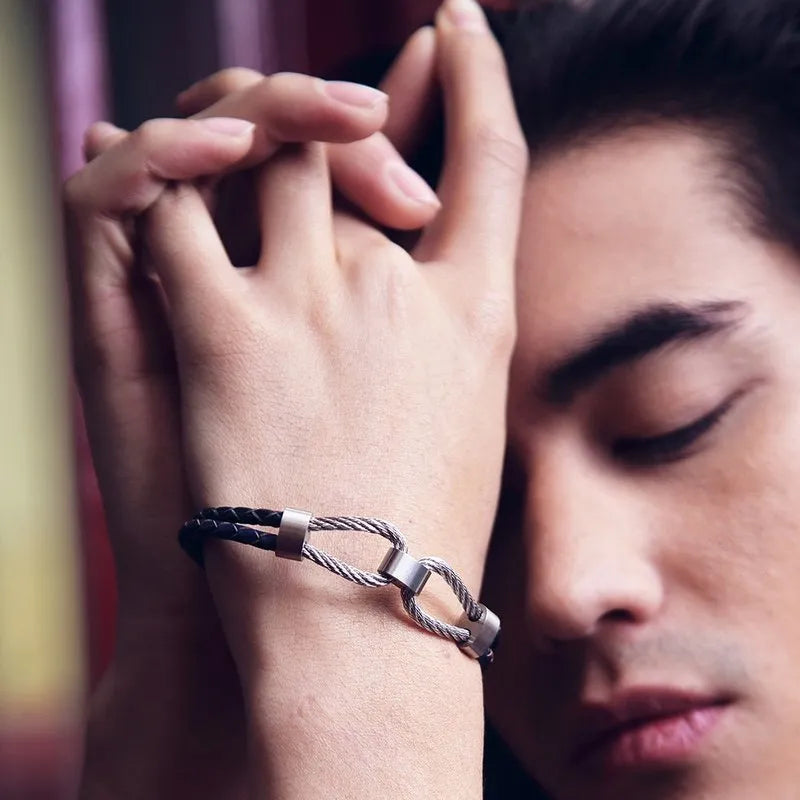 With their eyes closed, a person clasps their hands together while wearing the Volte leather and stainless steel men's bracelet.